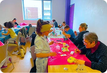 Groupe de famille faisant la décoration de boite en forme de cœur réuni par le secteur Famille du centre social